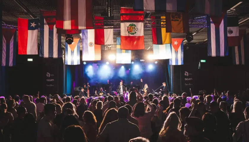 En stor publik njuter av en konsert i Uppsala, med flaggor från olika länder som hänger från taket.