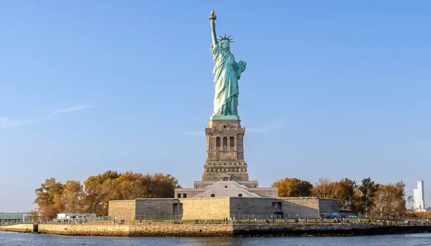 Gdzie jest Statua Wolności? Na wyspie Liberty Island w Nowym Jorku, dumnie wznosi się symbol wolności, otoczona wodą i jesiennymi drzewami.