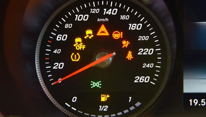 Cruscotto auto con varie luci della macchina spie accese: controllo stabilità, airbag, cinture, pressione pneumatici, carburante e fari.