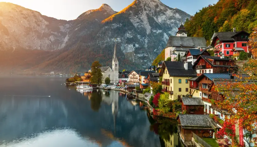 Hallstatt, Austria, un pueblo alpino con casas coloridas y una iglesia, reflejado en un lago sereno. Un ejemplo de los países más bonitos de Europa.