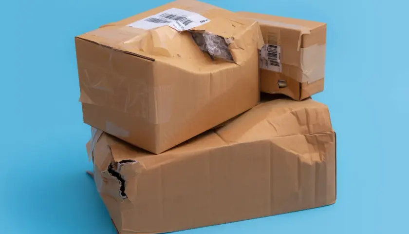 Dwie kartony, jedna na drugiej, z widocznymi uszkodzeniami i dziurami. Wygląda na to, że to uszkodzona paczka InPost.