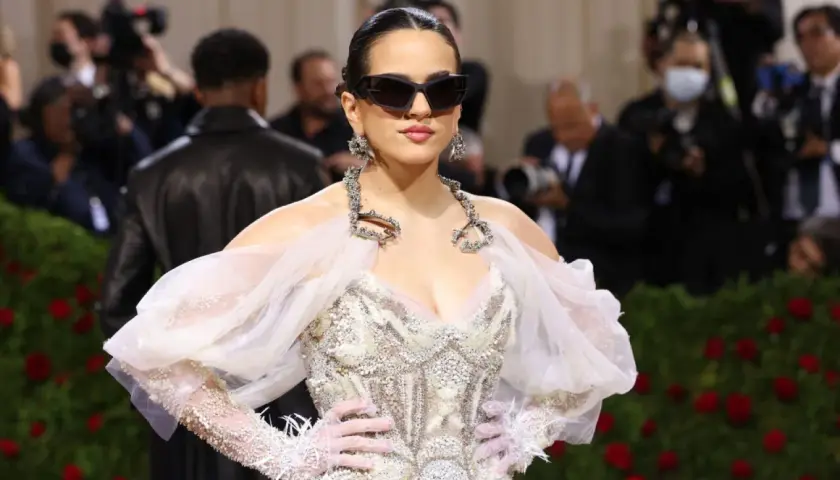 Rosalía deslumbrante en la Met Gala, con un vestido blanco adornado y gafas de sol audaces.