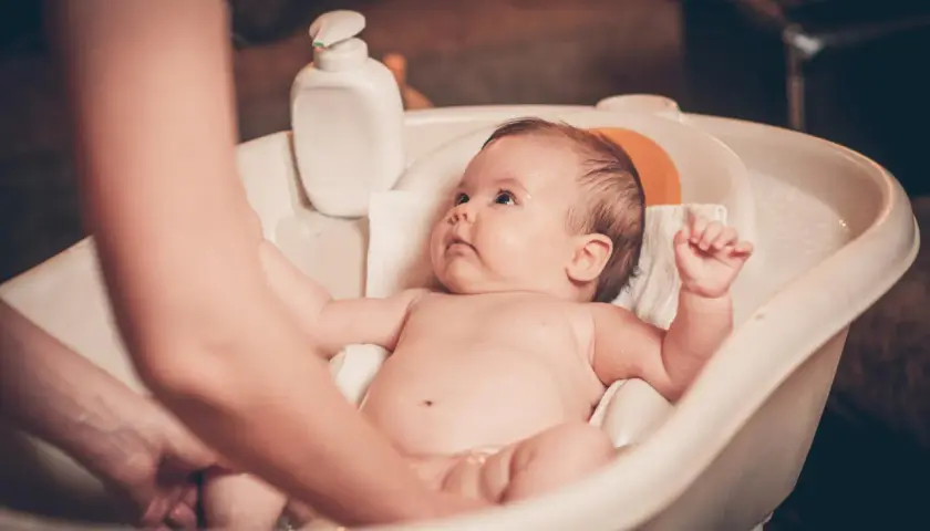Malutkie dziecko w wanience, rodzic delikatnie myje jego nóżki. Kąpiel to ważny rytuał, od kiedy kąpać dziecko codziennie? Od pierwszych dni życia!