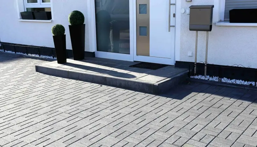 Nowoczesne aranżacje kostka brukowa wzory tworzą elegancki podjazd i schody przed domem.