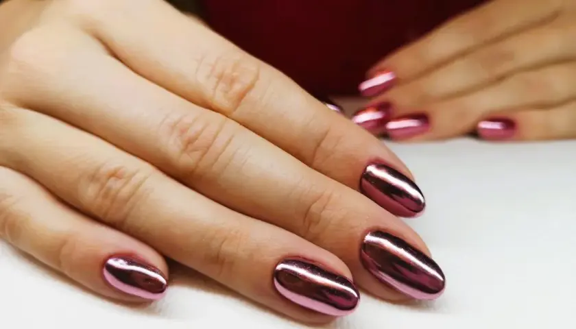 Dłonie z błyszczącym, metalicznym różowym manicure tytanowym. Czy ten efektowny manicure tytanowy rakotwórczy jest wart ryzyka?