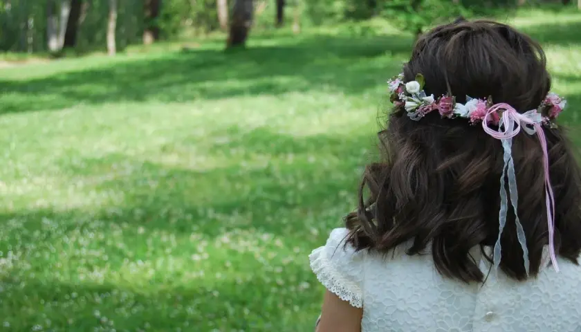 Niña con corona de flores y listones rosas, un ejemplo de peinados para niñas fáciles y bonitos.