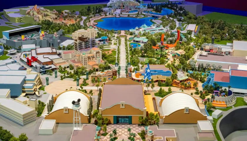 Maquette détaillée d'un parc d'attractions Disney avec lac, montagnes, bâtiments et attractions.