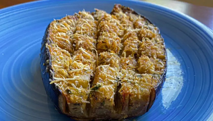 Melanzane a barchetta ripiene e gratinate, pronte per essere gustate su un piatto blu.