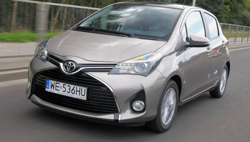 Szary Toyota Yaris w ruchu drogowym, widok z przodu.