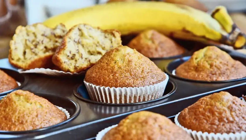 Muffin alla banana appena sfornati nella friggitrice ad aria, con una banana matura sullo sfondo.