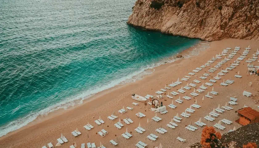 Piękna plaża z rzędami leżaków i turkusową wodą. Idealne miejsce, by zastanowić się, gdzie do Turcji na wakacje.