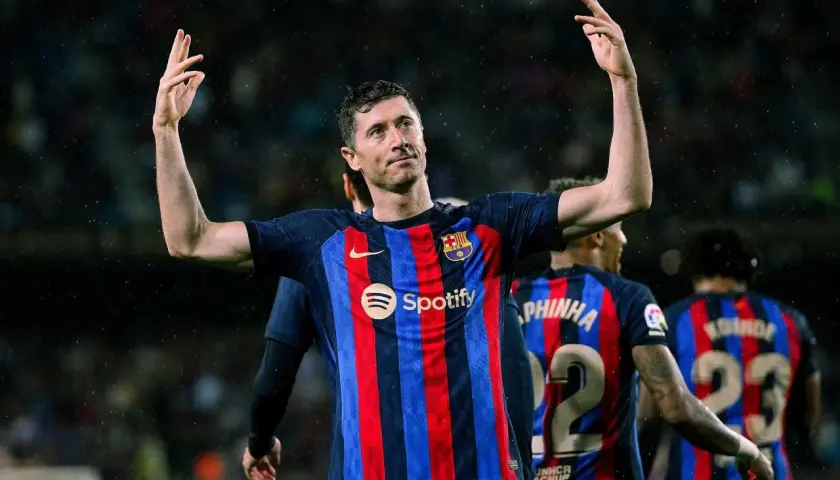 Robert Lewandowski, król strzelców, w koszulce Barcelony z podniesionymi rękami, świętuje zwycięstwo.