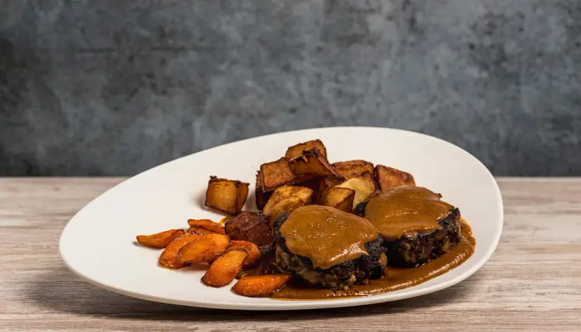 Plato de rabo de toro con patatas rústicas y zanahorias glaseadas. Una deliciosa receta para disfrutar.