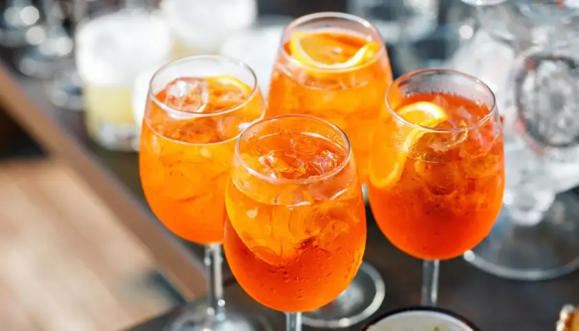 Cztery orzeźwiające drinki Aperol Spritz z lodem i plasterkami pomarańczy. Idealny aperol przepis na letnie popołudnie.