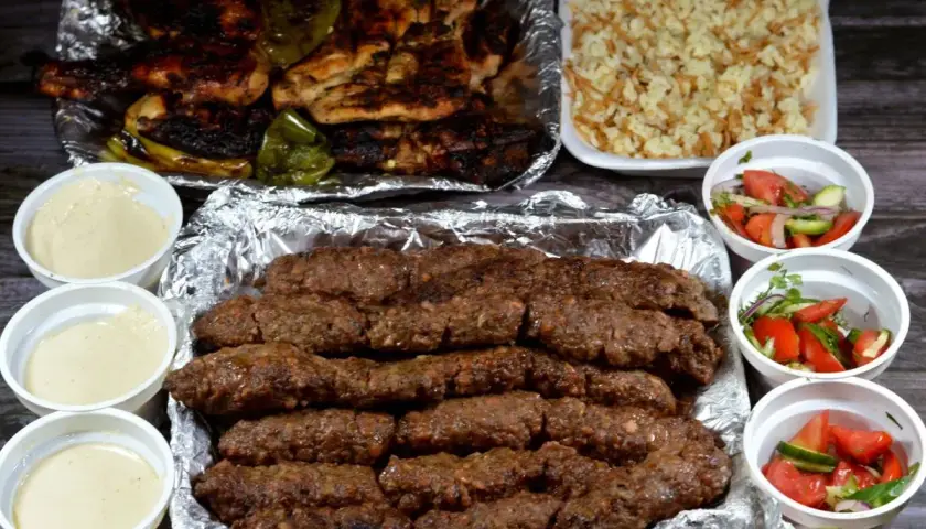 Pyszny kofta kebab z ryżem, sałatkami i sosami. Idealny posiłek dla miłośników mięsa.