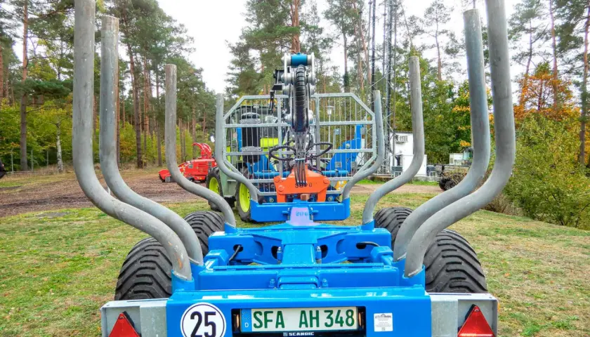 Ein blauer Rückewagen mit dem Kennzeichen SFA AH 348, bereit für den Einsatz im Wald. Dieses Folgekennzeichen landwirtschaft zeigt, dass er für den Transport von Holz bestimmt ist.