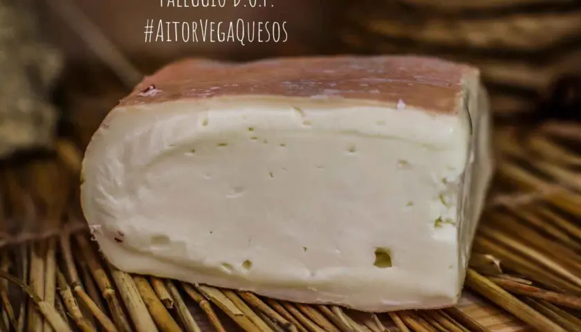 Un trozo de queso Taleggio D.O.P. con corteza rosada y pasta blanca, sobre paja. El queso Taleggio es fuerte y delicioso.