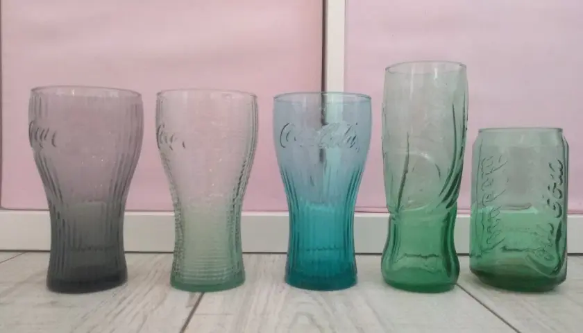 Pięć szklanek Coca-Cola w różnych kolorach. Zastanawiasz się, ile ml ma szklanka Coca Cola z Mc?