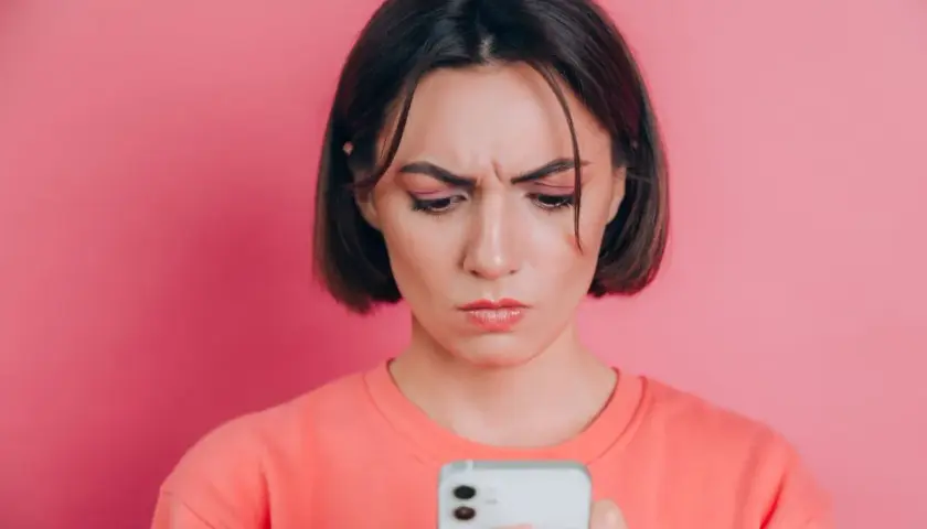 Zmarszczona kobieta patrzy na telefon, zastanawiając się, jak poprawić jakość zdjęć na Instagramie.
