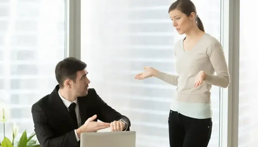 Mężczyzna w garniturze pokazuje zegarek, kobieta gestykuluje. Dyskusja o wezwaniu do sądu a praca.