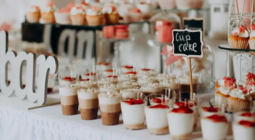 Un buffet de desserts festif, parfait pour une idée repas mariage été, avec des cupcakes, verrines et macarons.