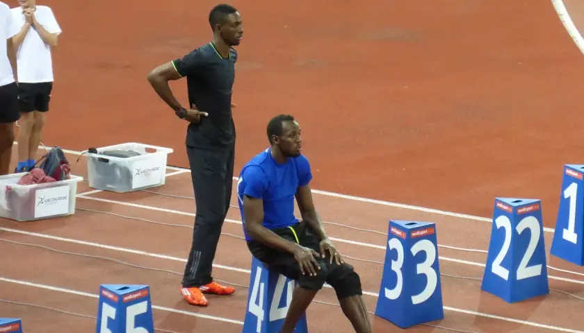 Usain Bolt, siedzący i stojący na bieżni, przypomina o jego rekordowej prędkości, która osiągnęła ponad 44 km/h.