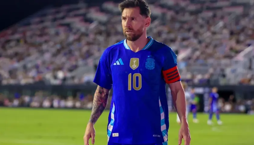 Messi w niebieskiej koszulce reprezentacji Argentyny, z numerem 10 na piersi, na tle trybun pełnych kibiców.