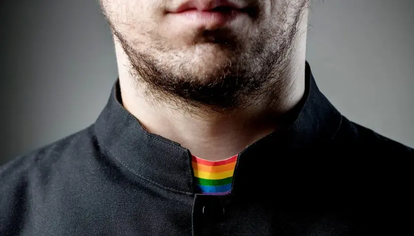 Broda i usta mężczyzny w czarnej koszuli. Widoczny tęczowy kołnierzyk, symbolizujący, co to jest pastor otwarty na wszystkich.