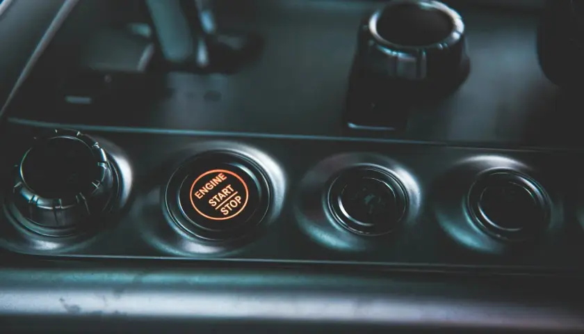 Podświetlany przycisk "ENGINE START STOP" w nowoczesnym samochodzie. Obok niego przyciski wyboru trybu jazdy.