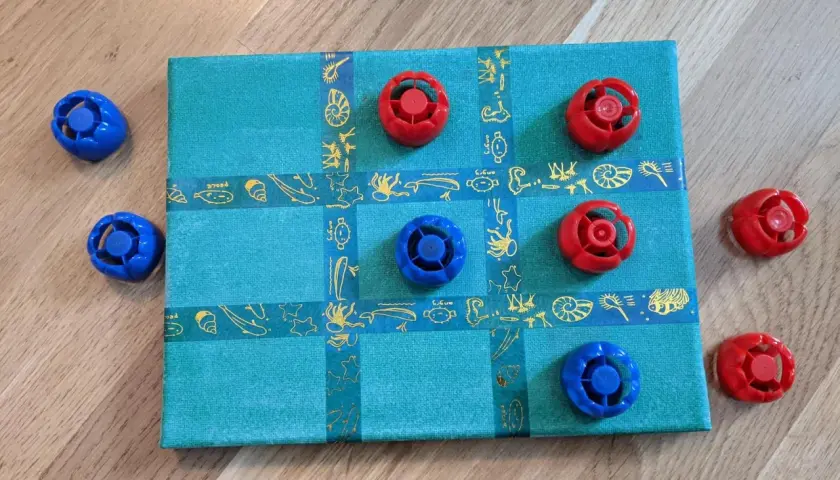 Selbstgemachtes Spielbrett mit blauen und roten Spielfiguren. Ein tolles Bastelprojekt für Kinder!