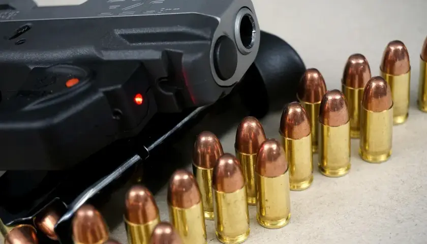 Pistolet i naboje, gotowe do akcji. To obraz, który symbolizuje produkcję broni i jej potencjalne użycie.