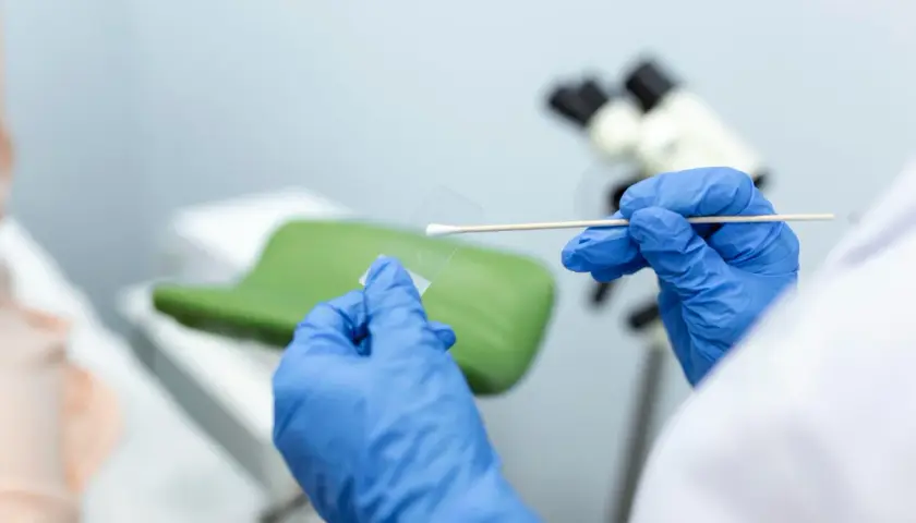 Ręce w niebieskich rękawiczkach przygotowują próbkę do badań cytologicznych. Wyniki będą gotowe wkrótce.