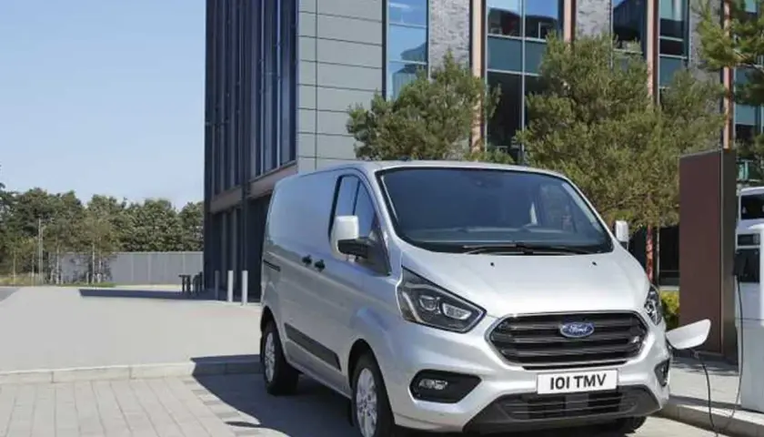 Furgoneta Ford Transit plateada cargando, con un edificio moderno al fondo. La presión de los neumáticos es clave para su eficiencia.