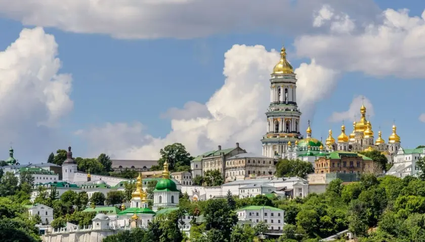 Kijów, z czego słynie Ukraina: złote kopuły cerkwi i majestatyczna dzwonnica Ławry Peczerskiej na tle błękitnego nieba.