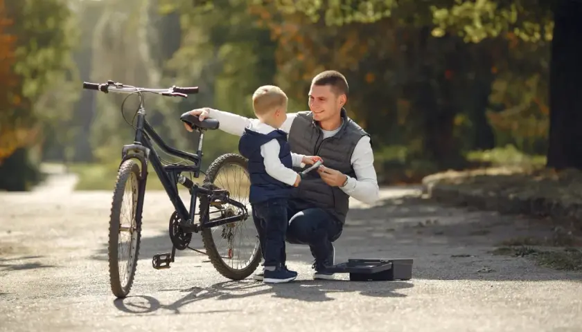 Tata pokazuje synowi, jak działa hamulec. To ich pierwszy rower dla dziecka, gotowy na wspólne przygody.
