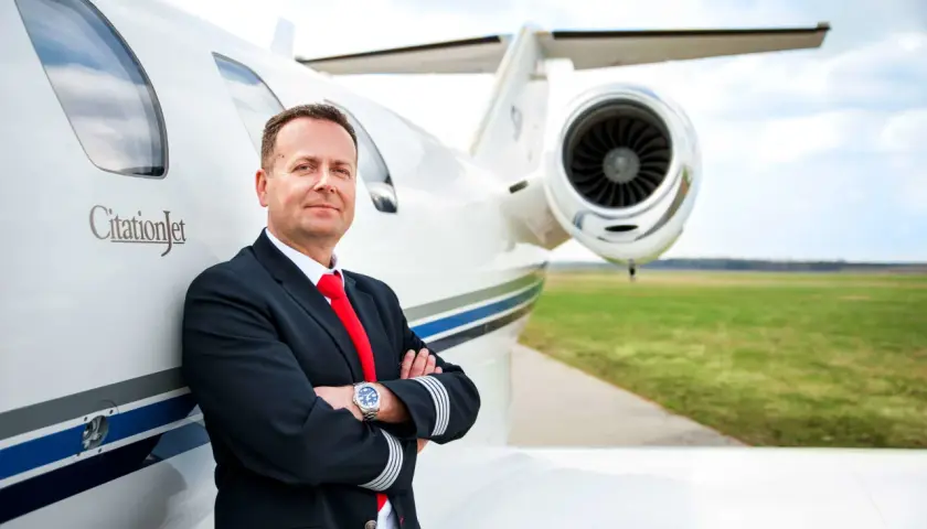 Pilot w mundurze przy CitationJet. Marzysz, jak zostać pilotem samolotu pasażerskiego? To zdjęcie może być inspiracją.