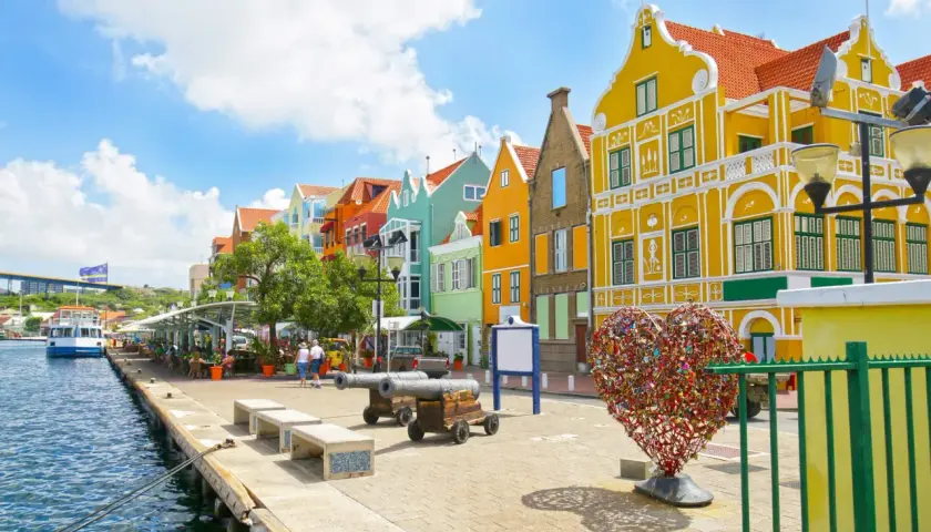 Kolorowe budynki, serce z kłódek i armaty nad wodą – idealne miejsce na curacao wakacje.