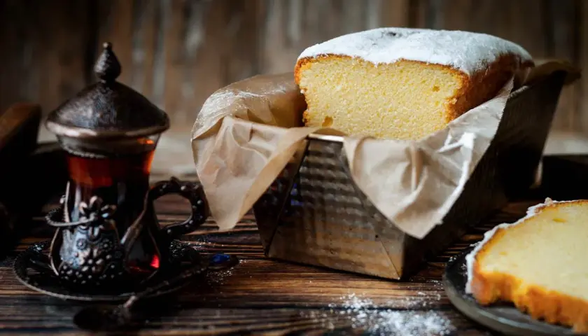 Puszysta babka włoska, oprószona cukrem pudrem, czeka na degustację obok aromatycznej herbaty w orientalnej filiżance.