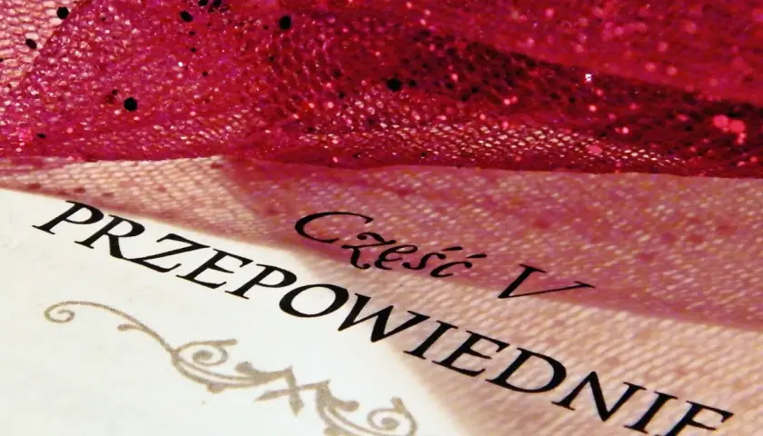 Część V "Przepowiednie" z "The Night Circus" pod błyszczącą, różową tkaniną.