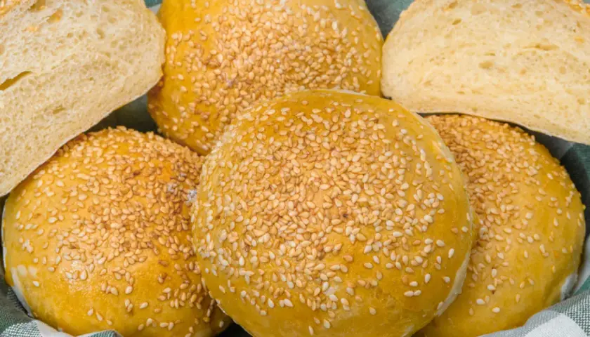 Koszyk pełen pysznych, złotych bułek bez drożdży, posypanych sezamem. Idealne na kanapki i burgery.