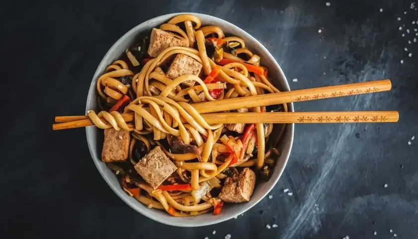 Miseczka pełna makaronu udon z tofu i warzywami, gotowa do jedzenia. Idealny makaron udon przepis na szybki obiad.