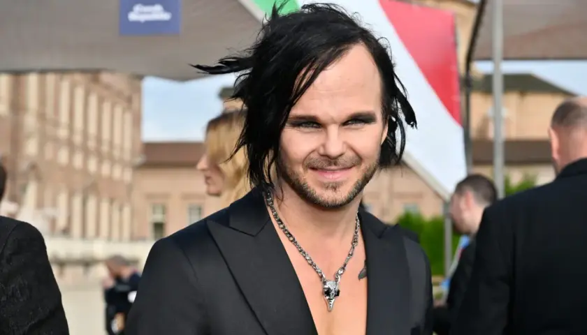 The Rasmus wokalista z charakterystyczną fryzurą i makijażem, w czarnym garniturze i naszyjnikiem z czaszką.