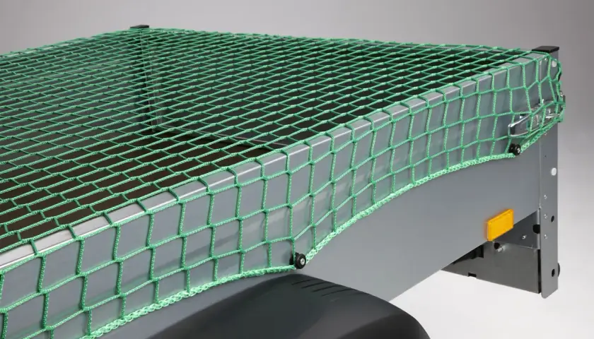 Grünes Abdecknetz sichert die Ladung auf einem Anhänger. Perfekt für den Transport von Gartenabfällen oder sperrigen Gegenständen.