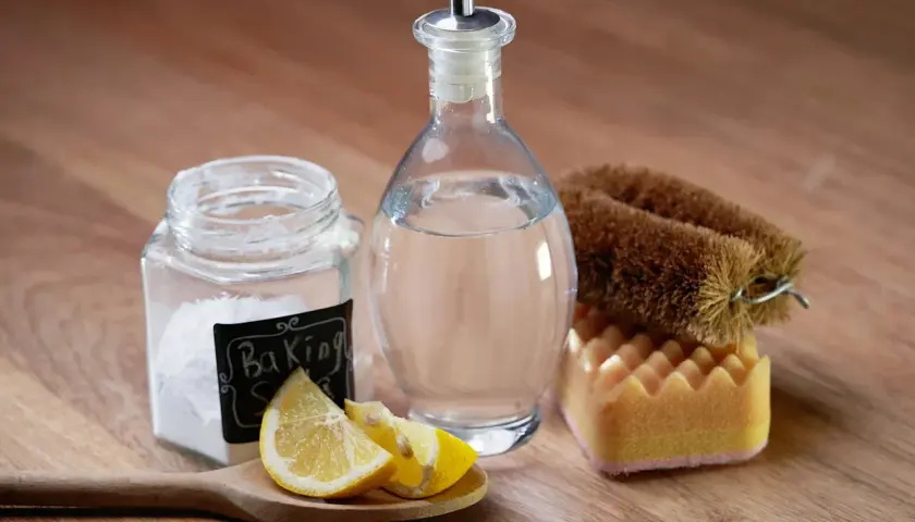 Natürliche Reinigungsmittel: Natron, Zitrone und Essigreiniger-Flasche mit Bürste und Schwamm.