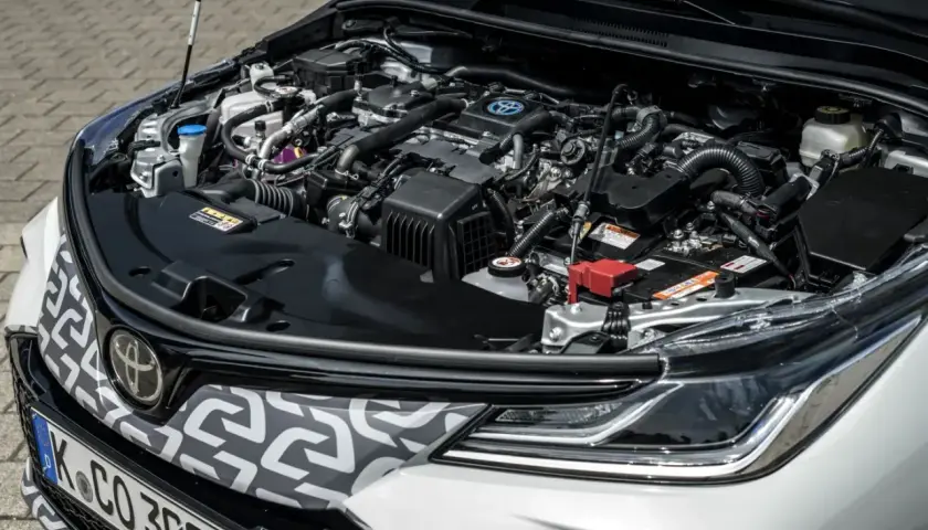 Silnik hybrydowy Toyoty Corolli 2022, z widocznym logo Toyoty i elementami układu napędowego.