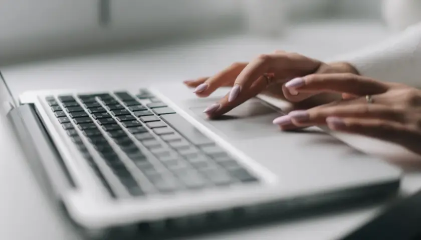 Dłonie z różowym lakierem na paznokciach pracują na touchpadzie laptopa. To efekt pracy nad projektem, który wymaga precyzji, jak druk sd-3.