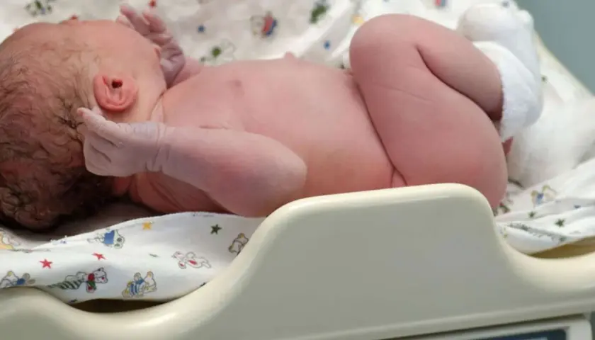 Neugeborenes Baby auf einer Waage. Das Geburtsgewicht des Babys wird ermittelt.