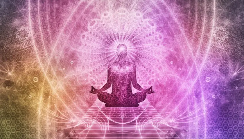 Sylwetka w pozycji lotosu, otoczona świetlistymi wzorami, symbolizująca przebudzenie energii kundalini.