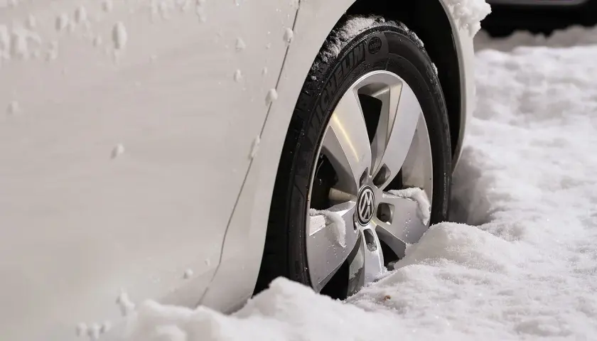 Biały samochód z felgami i oponami Michelin w śniegu. Zastanawiasz się, jakie opony zimowe wybrać?