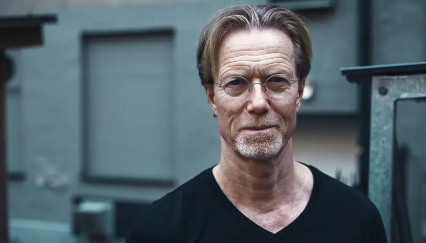 Porträtt av Emil Eiman Roslund med glasögon och skäggstubb, klädd i svart t-shirt.